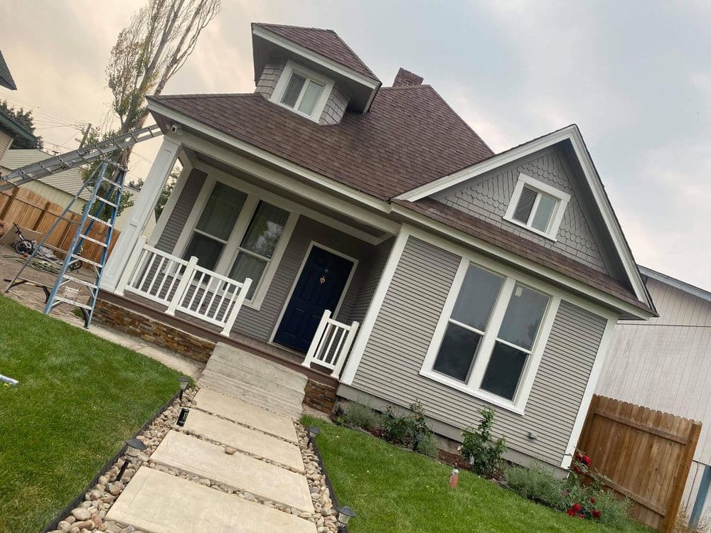 Victorian-style house with gray siding, blue door, and landscaped yard.
