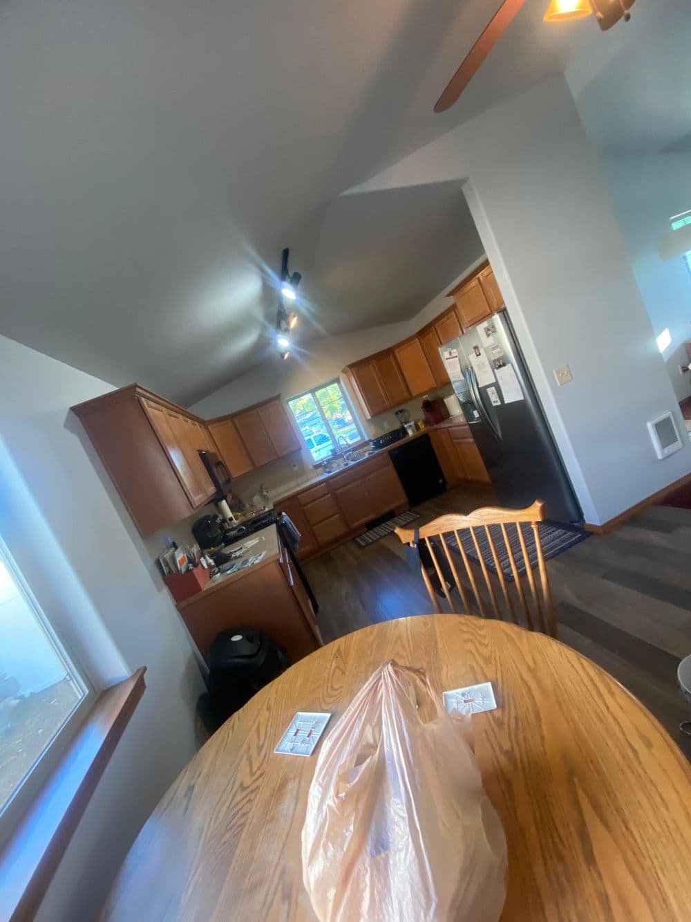 Bright kitchen with wooden cabinets, dining table, and modern appliances, featuring natural light.