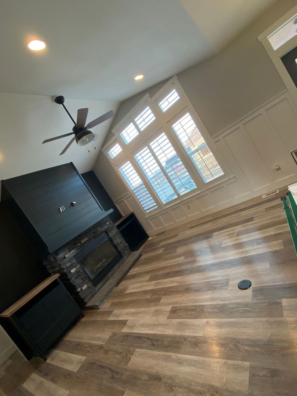 Modern living room with hardwood floors, stone fireplace, and large windows. Ideal for cozy gatherings.