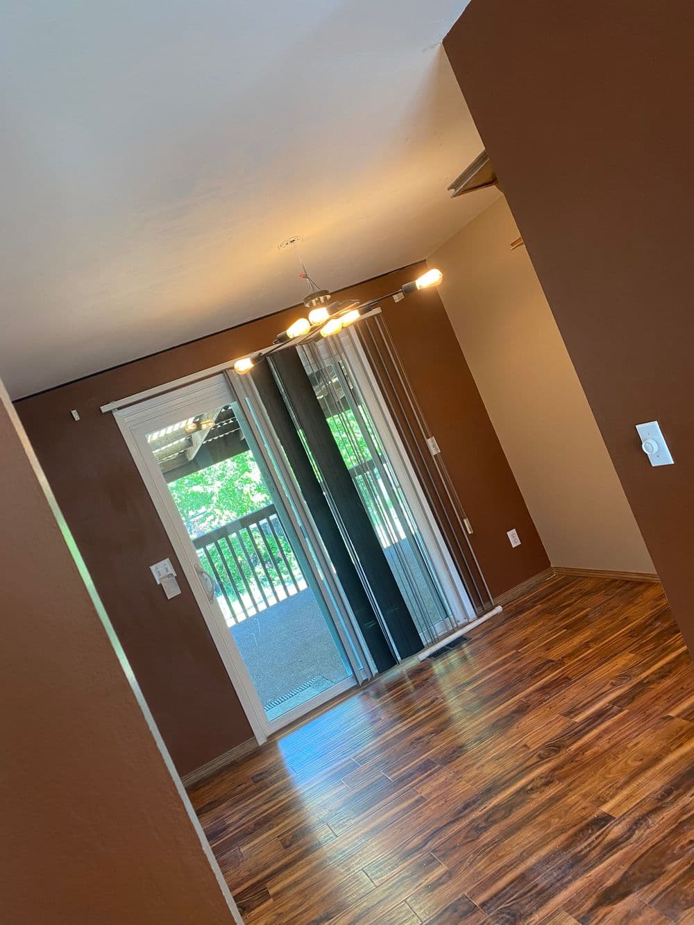 Cozy room with brown walls, wood flooring, and sliding glass doors to a patio.