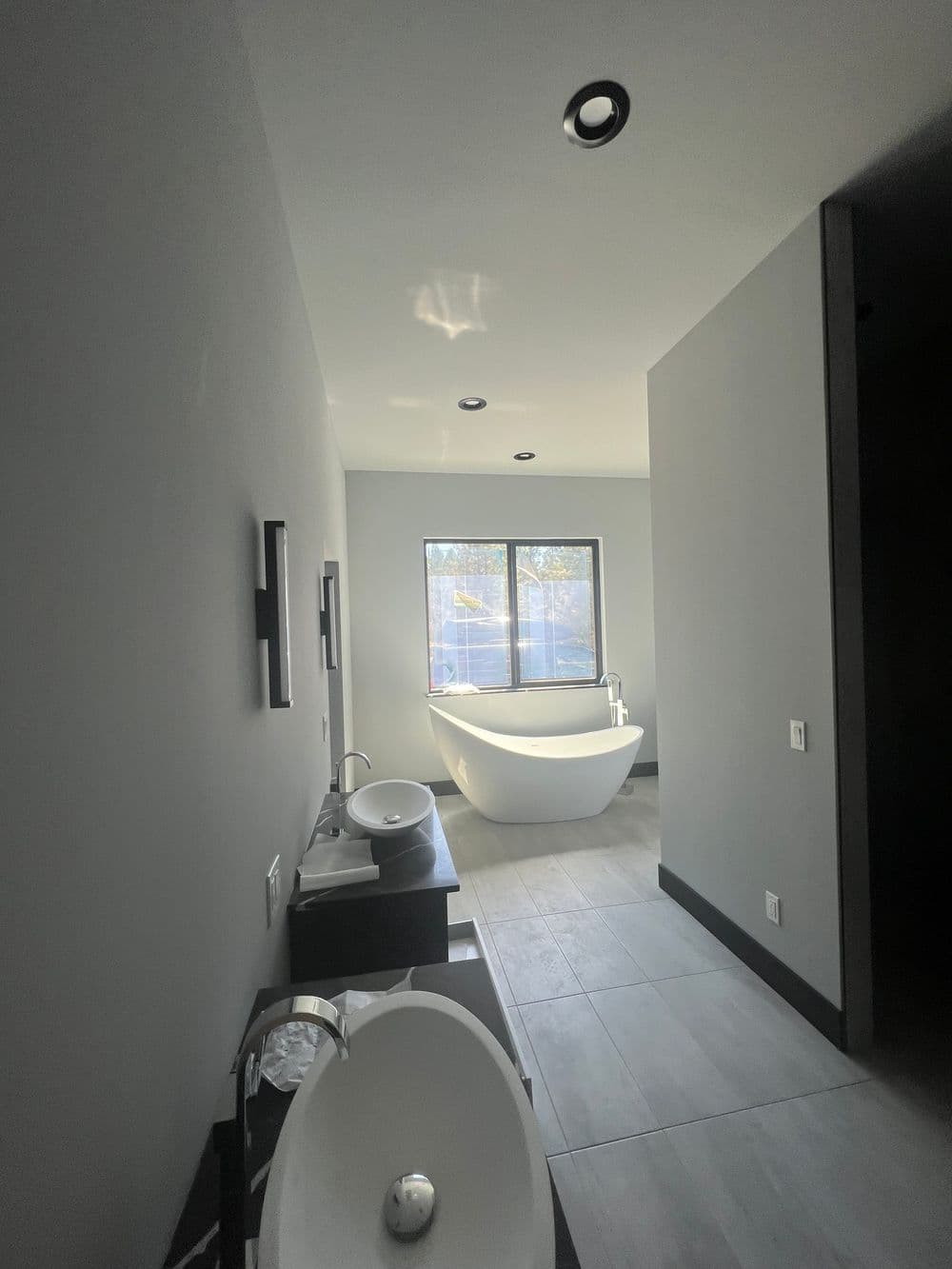 Modern bathroom interior featuring a freestanding tub, sleek fixtures, and ample natural light.
