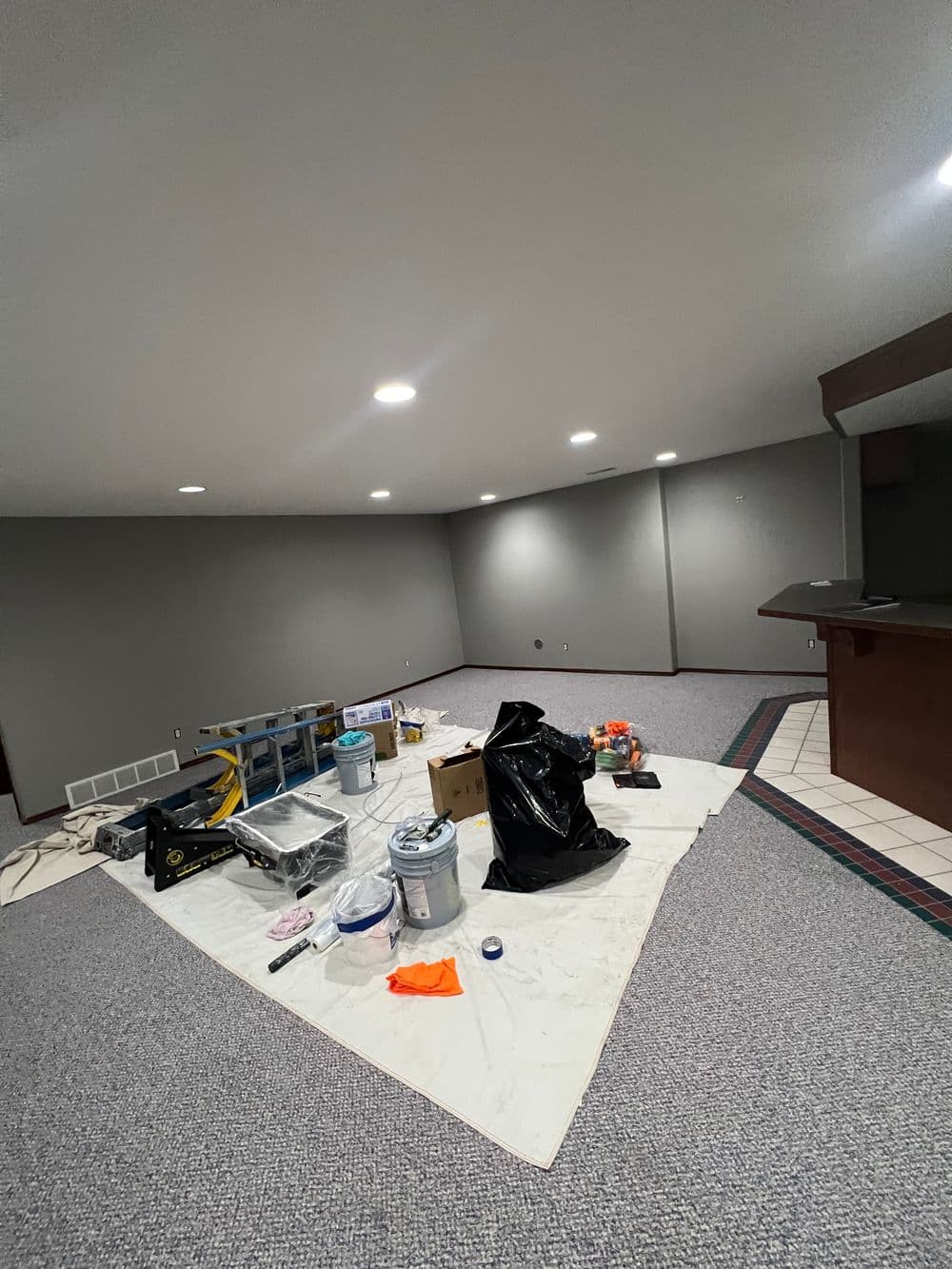 Renovation in progress: empty room with painting supplies and tools scattered on the floor.