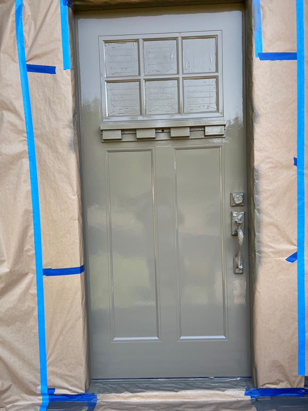 Freshly painted front door with protective masking tape and paper around the frame.
